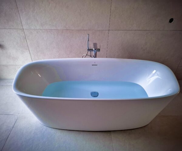 Lichtdurchflutetes Bad mit begehbarer Dusche, eleganten Armaturen und Holzakzenten.