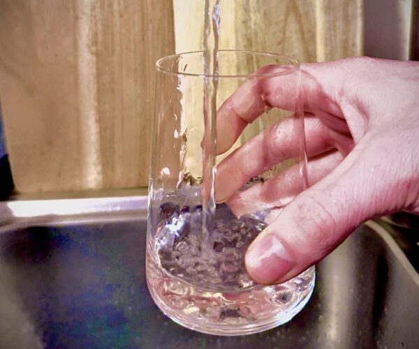 Techniker im Firmenpolo prüft Heizungswerte mit Tablet, modernes Umfeld.